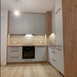 Nowoczesne meble w eleganckim, szarym wykończeniu z ciepłymi, drewnianymi akcentami. 