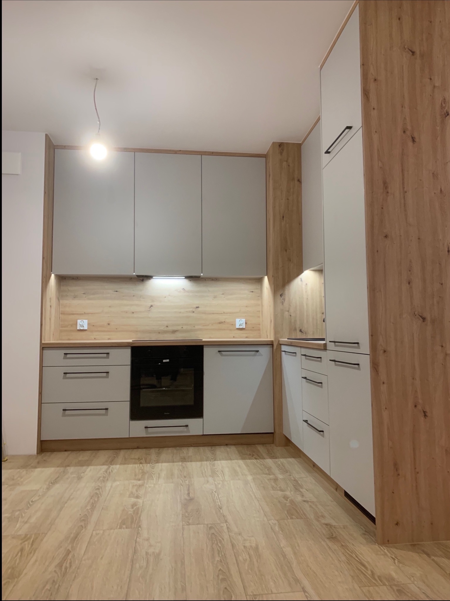 Nowoczesne meble w eleganckim, szarym wykończeniu z ciepłymi, drewnianymi akcentami.