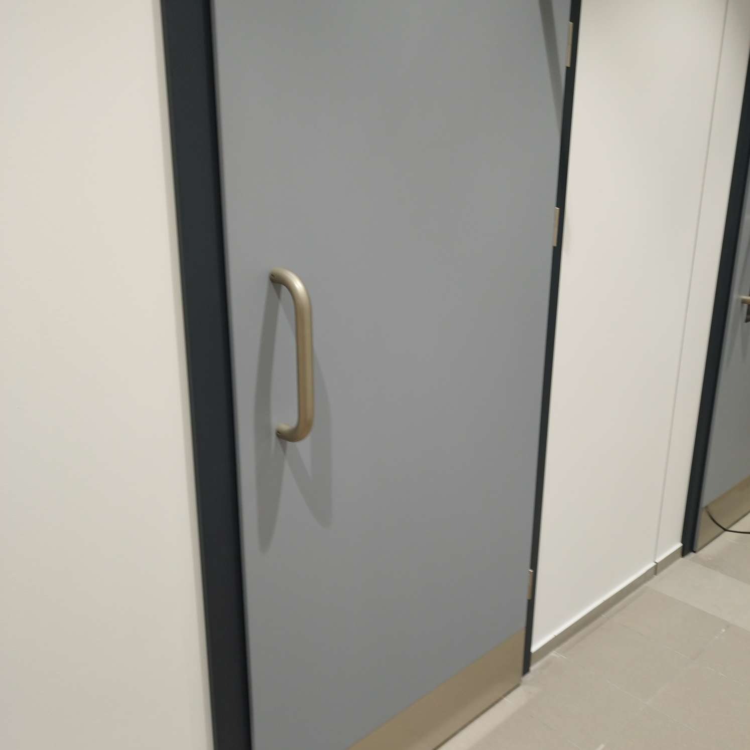 Szara, czysta powierzchnia drzwi z metalową klamką w biurze w Cięcinie, po profesjonalnych pracach porządkowych.