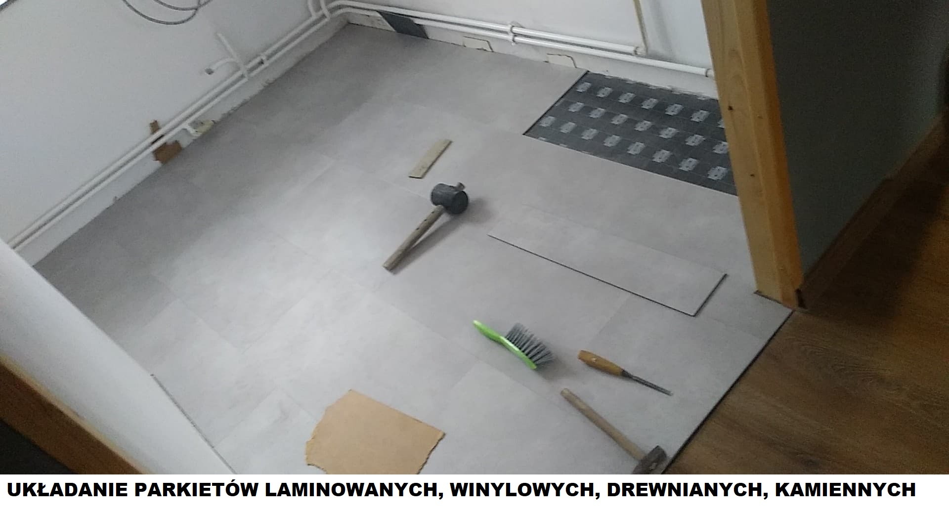 Układanie szarych paneli podłogowych w pomieszczeniu, widoczne narzędzia: gumowy młotek, szczotka, dłuto, fragmenty podkładu i niedokończona powierzchnia obok kratki wentylacyjnej.