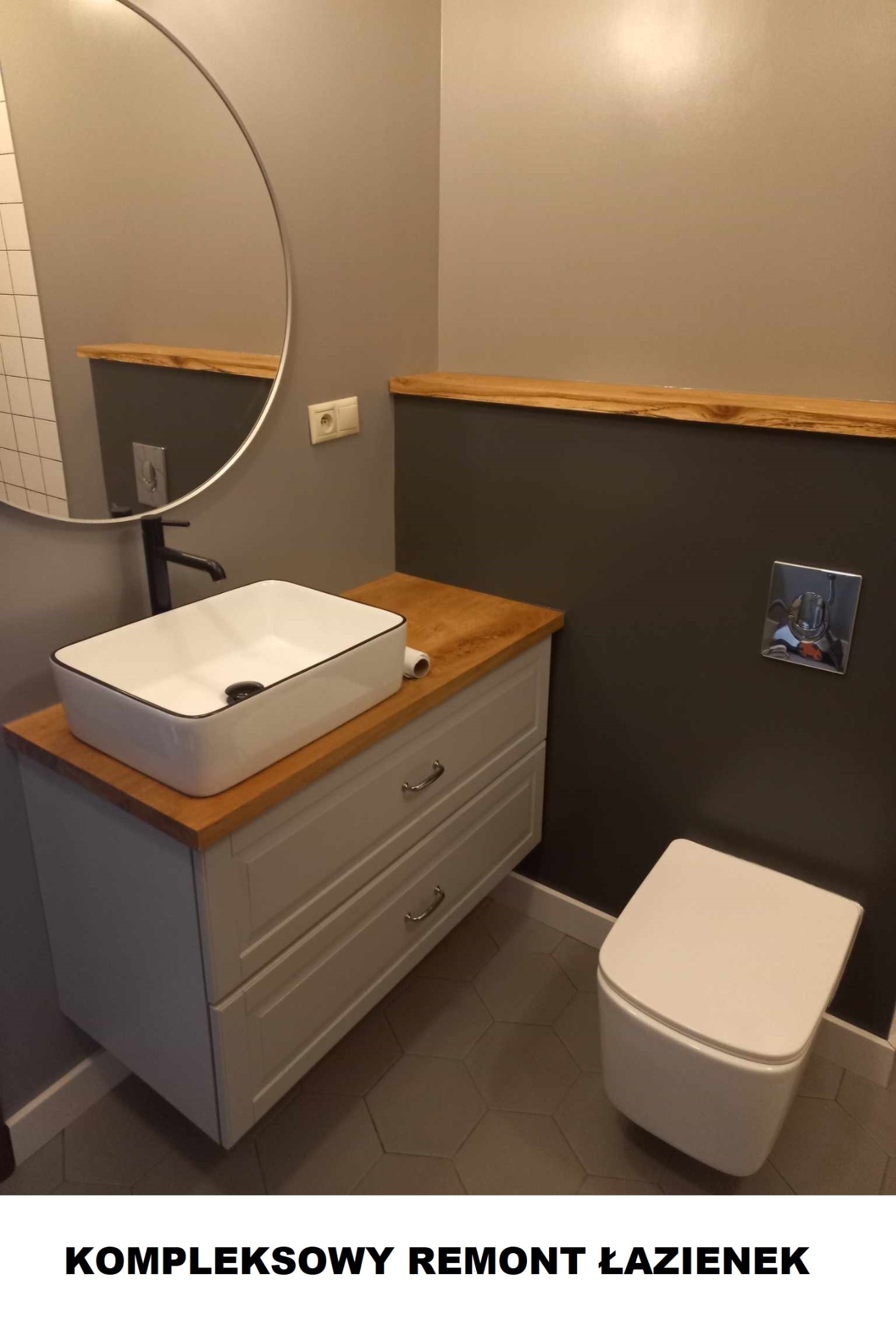 Nowoczesna łazienka z umywalką nablatową w kształcie prostokąta z czarnym obramowaniem, okrągłe lustro, drewniany blat i heksagonalne płytki podłogowe w odcieniach szarości.