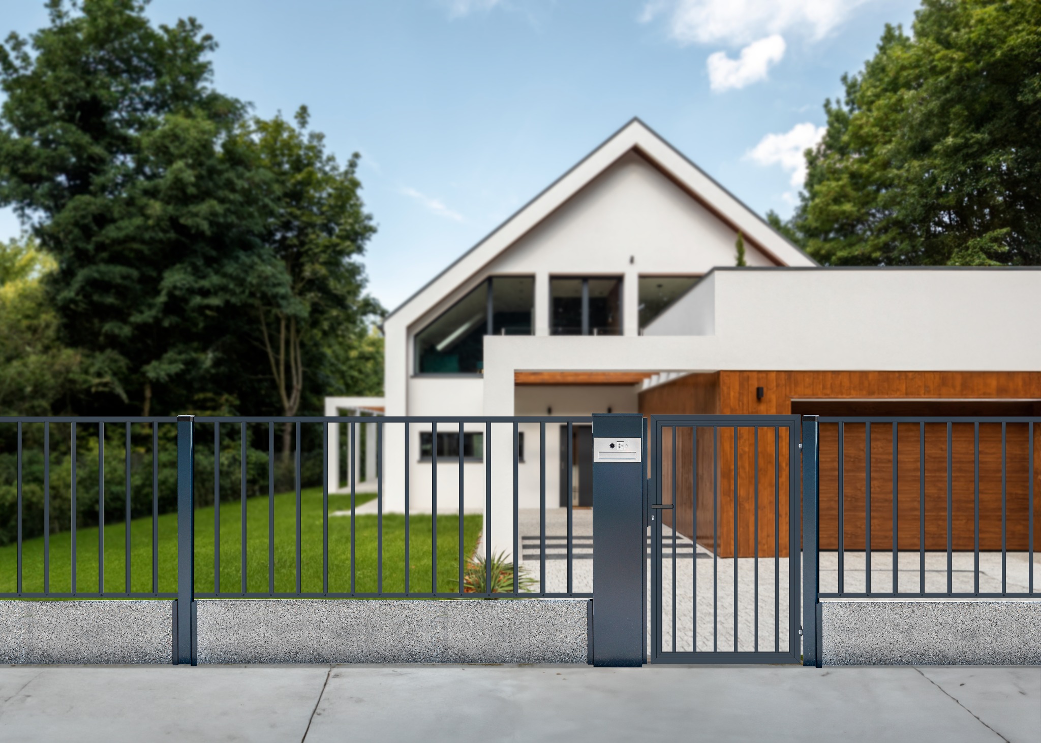 Nowoczesne ogrodzenie z metalowych paneli i furtką, z szarą podmurówką, na tle białego domu z elementami z drewna.