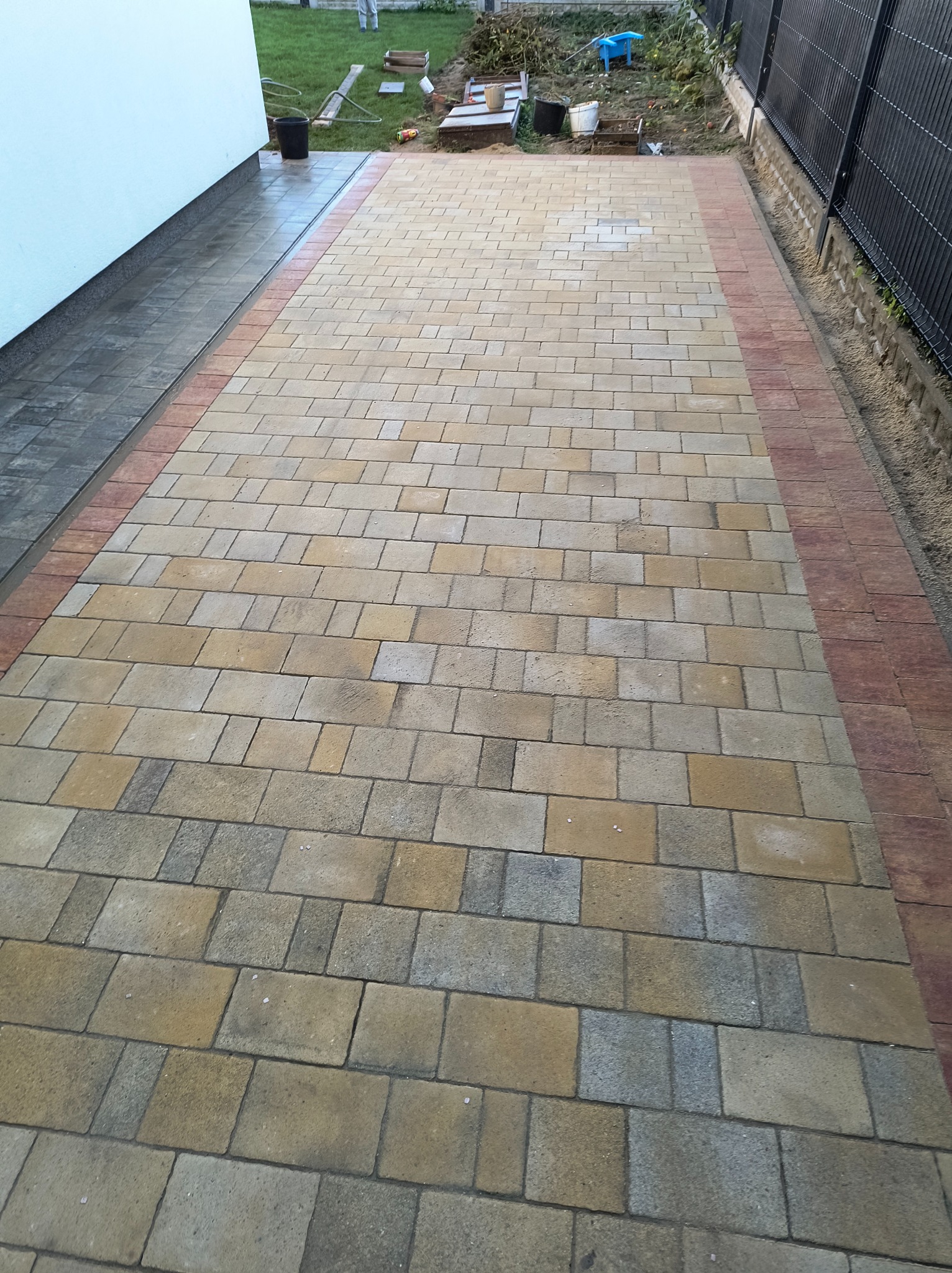 Ułożona kostka brukowa w odcieniach beżu i szarości z bordową obwódką, widok z perspektywy