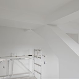 Sebastian Buda firma wykonczeniowa - Świeżo pomalowane na biało poddasze ze skosami i belkami, widoczne rusztowanie malarskie i otwór drzwiowy.