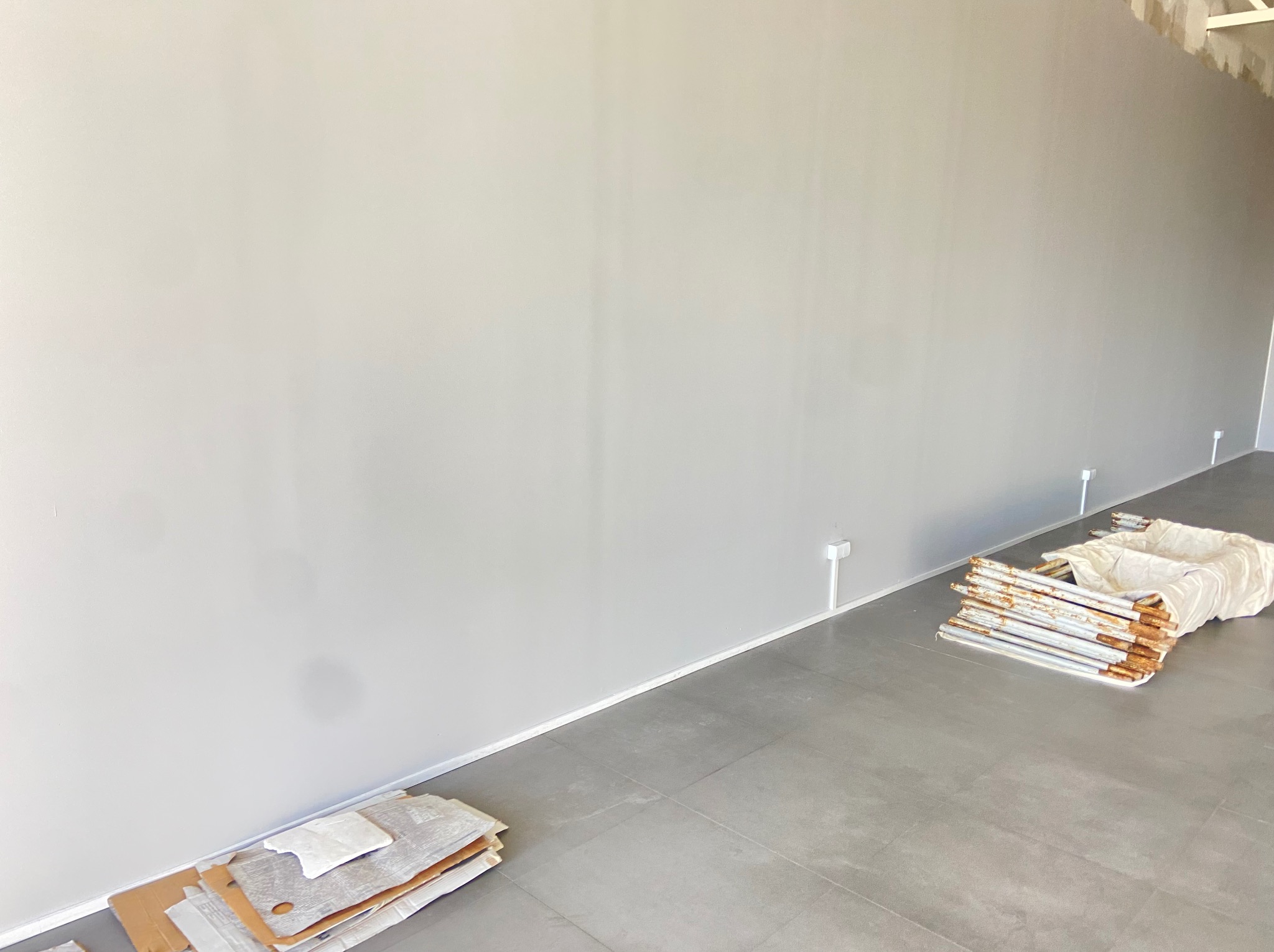 Białe gniazdka elektryczne przy ścianie w Rynarzewie. Przygotowania do montażu. Elementy instalacji i zabezpieczenia na podłodze.