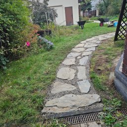 Mateusz Fraszczyński - Ścieżka z nieregularnych płyt kamiennych, wysypana drobnym żwirem, prowadząca przez trawnik w ogrodzie, zakończona kratką drenażową