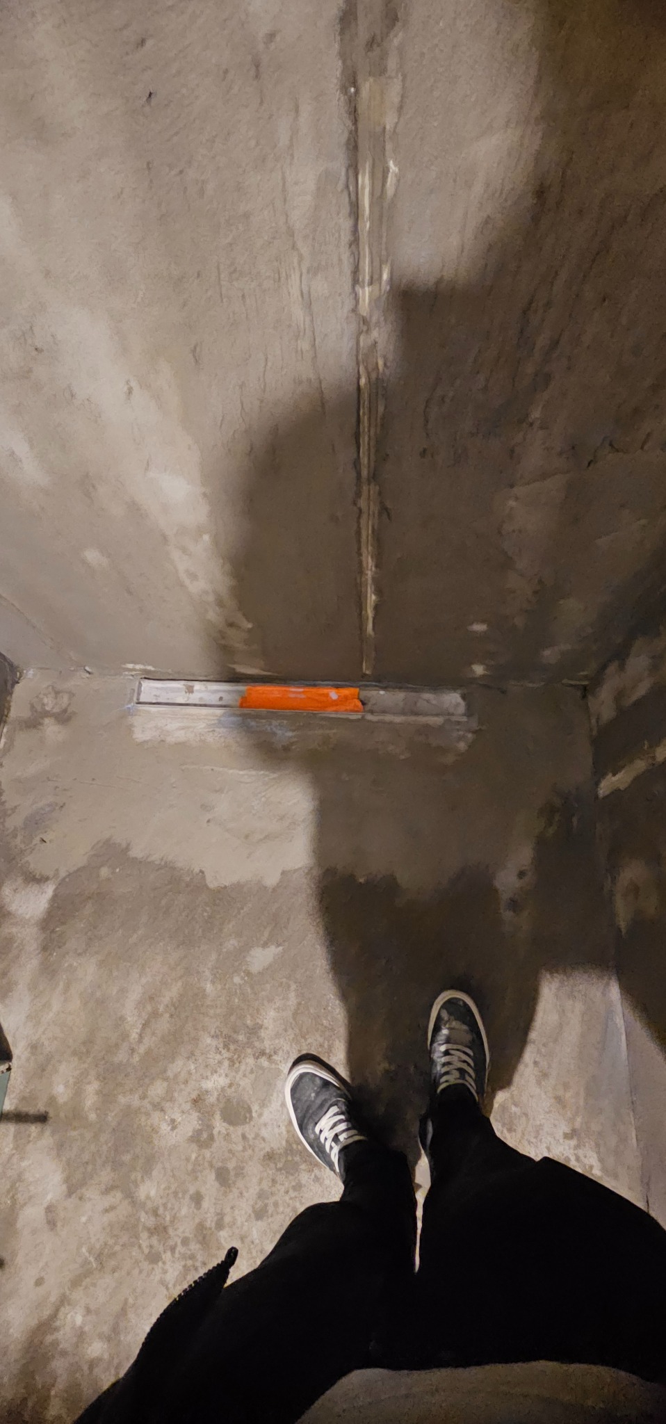 Przygotowanie podłoża pod prysznic w Poznaniu. Widoczny odpływ liniowy i surowy beton na ścianach. Etap prac wykończeniowych w łazience.