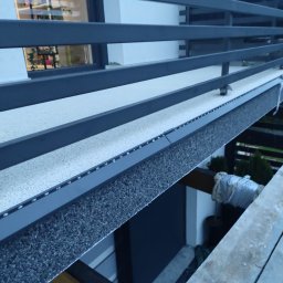 DAMIAN SITEK KAMIENNE DYWANY - Zabudowany balkon z szarą, poziomą konstrukcją i oświetleniem LED, widok z dołu.