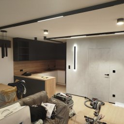 Fix&Finish Robert Tomala - Nowoczesne wnętrze w trakcie wykończenia: czarna zabudowa kuchenna, oświetlenie liniowe, szpachlowana ściana z ukrytymi drzwiami, narzędzia na podłodze.