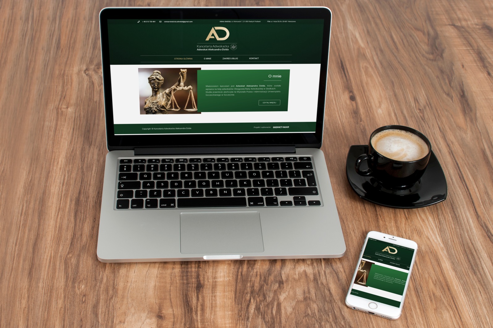Laptop i smartfon wyświetlają stronę internetową kancelarii adwokackiej na drewnianym biurku, obok filiżanka kawy.