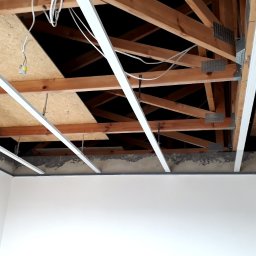 firma remontowo-budowlana Cycuś-Glancuś.pl - Montaż profili sufitowych podwieszanych na drewnianej konstrukcji stropu, widoczne przewody elektryczne i płyta OSB.