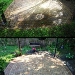 Hydro Clean Dawid Łukaszewicz - Porównanie stanu kostki brukowej przed i po czyszczeniu: widoczna różnica w kolorze i czystości, z okrągłą studzienką w centrum i elementami ogrodu w tle.