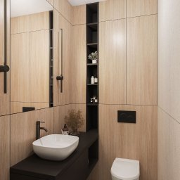 KASME studio - Nowoczesna łazienka z drewnopodobnymi panelami ściennymi, umywalką nablatową na czarnej szafce, toaletą podwieszaną i geometryczną mozaiką podłogową. W tle widoczna wnęka z półkami i dekoracjami.