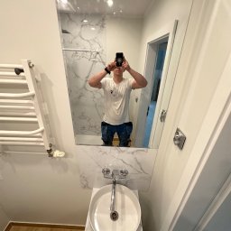 Well Done Krystian Chojnicki - Nowoczesna łazienka z umywalką nablatową, lustrem z odbiciem osoby robiącej zdjęcie i grzejnikiem drabinkowym na ścianie