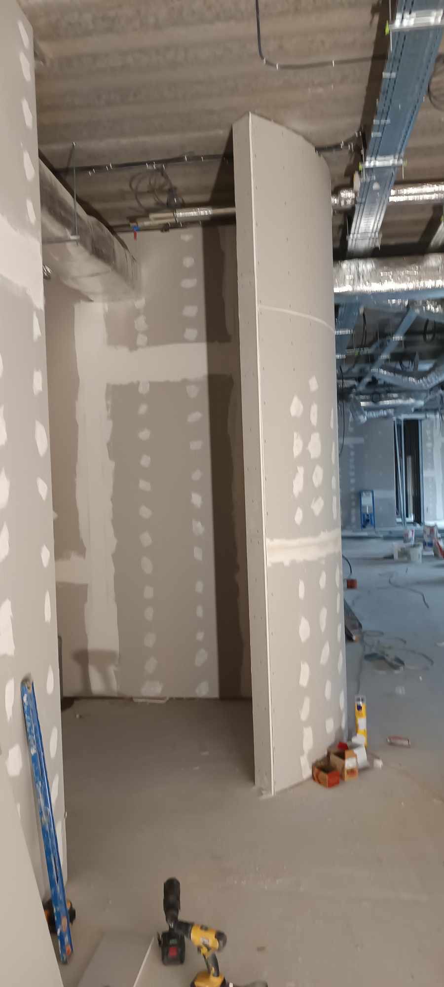 Montaż ścian działowych z płyt w Łodzi: widok na surowy stan wnętrza z widocznymi elementami konstrukcyjnymi i narzędziami pracy, przygotowanego do dalszych prac wykończeniowych.