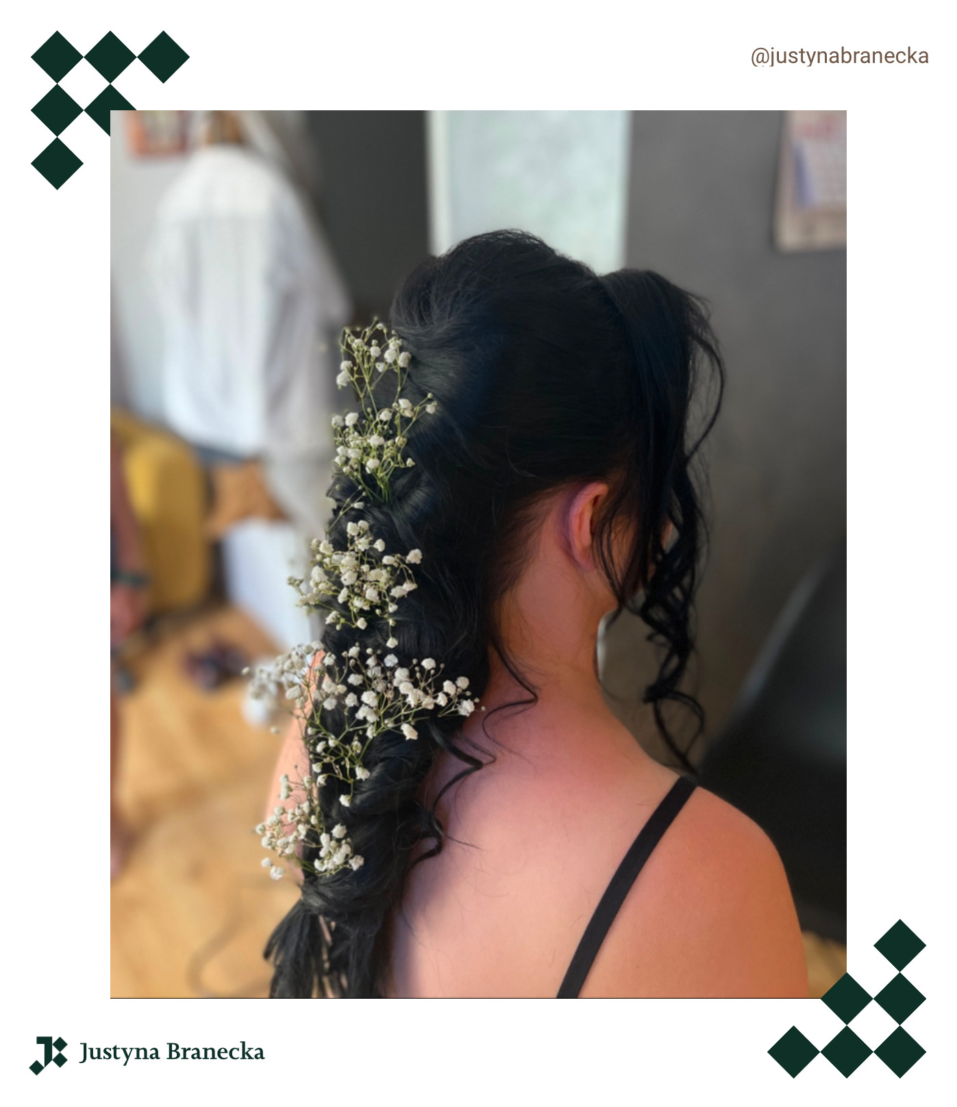 Upięta, ciemna fryzura z wplecionymi drobnymi, białymi kwiatami, widok z tyłu, na tle jasnego wnętrza.