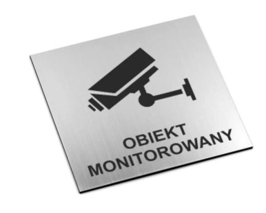 Metalowa tabliczka informacyjna z czarną ikoną kamery przemysłowej i napisem 'OBIEKT MONITOROWANY' na białym tle.
