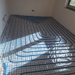 Hydro-Tech - Niebieskie rury ogrzewania podłogowego KELLER na macie izolacyjnej z siatką, w pomieszczeniu z oknem i okablowaniem, Trąbki.