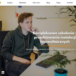 LoveWeb - Młody mężczyzna w bluzie z kapturem siedzi przy biurku z klawiaturą i rośliną w doniczce, przeglądając stronę internetową kielgo.pl dotyczącą szkoleń z projektowania instalacji fotowoltaicznych...