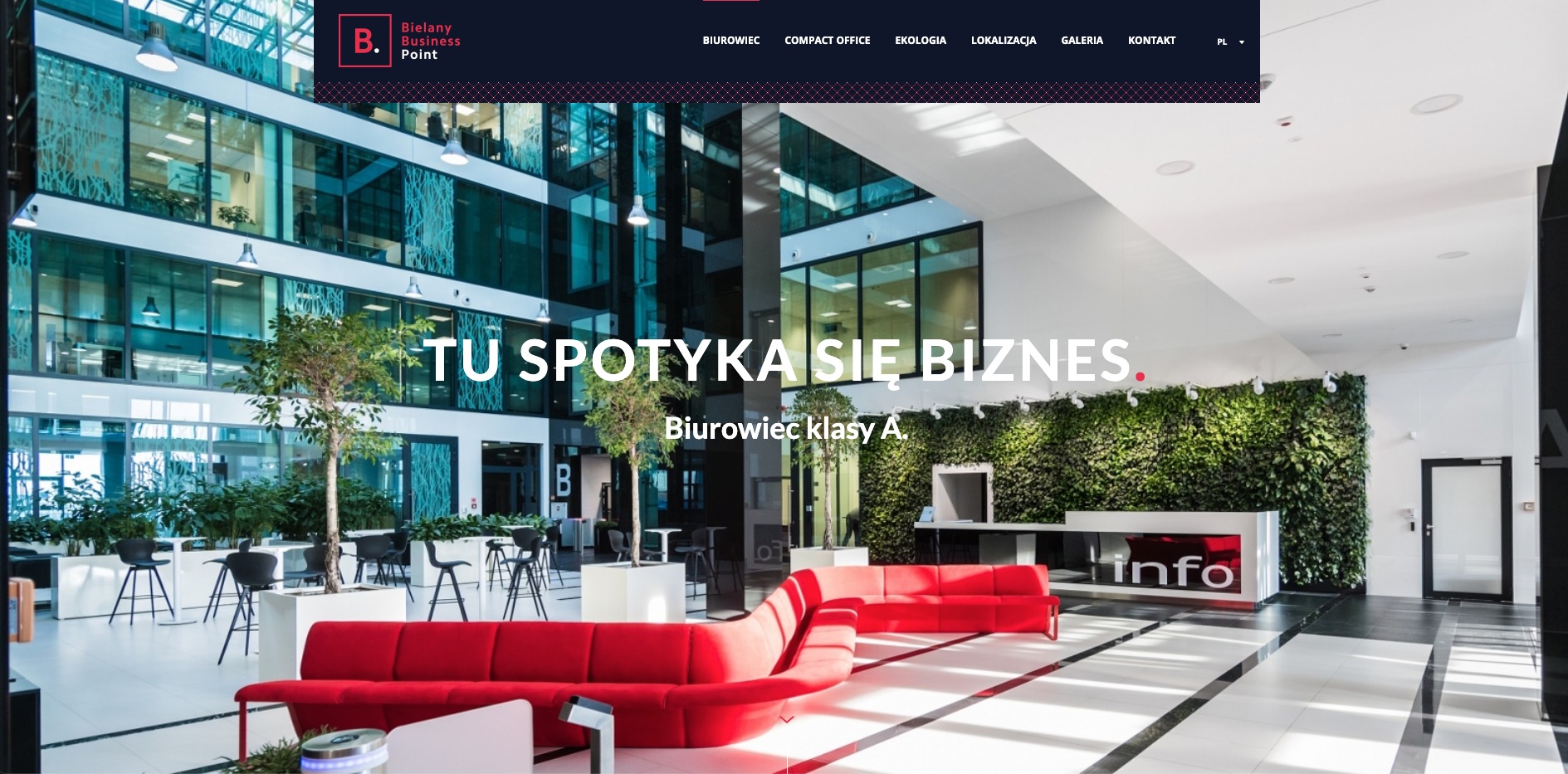 Wnętrze nowoczesnego biurowca klasy A z recepcją, czerwonymi sofami, zieloną ścianą z roślin i przeszkleniami