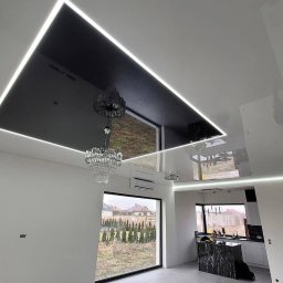 Master bud I Prace remontowe I Budownictwo I Warszawa - Nowoczesne wnętrze z czarnym, podwieszanym sufitem z oświetleniem LED, kryształowym żyrandolem i widokiem na ogród przez duże okno.