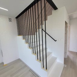 Master bud I Prace remontowe I Budownictwo I Warszawa - Nowoczesne, białe schody z czarnymi, pionowymi balustradami i drewnianymi podłogami, wykończenie wnętrza domu.