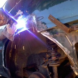 RRR Renowacja - Spawanie nadkola samochodu z widocznymi iskrami i spawarką w rękach spawacza w rękawicach ochronnych.