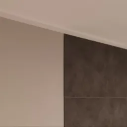 Fragment pomalowanej na beżowo ściany sąsiadującej z ciemnoszarą ścianą wykończoną płytkami imitującymi kamień, widoczne białe listwy przysufitowe.