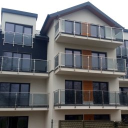 INOX-STAL SC - Trzypiętrowy budynek mieszkalny z balkonami zabezpieczonymi szklanymi taflami w stalowych ramach.