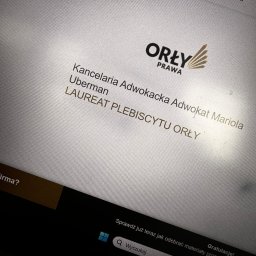KANCELARIA ADWOKACKA ADWOKAT MARIOLA UBERMAN - Ekran laptopa wyświetlający logo i nazwę Kancelarii Adwokackiej Uberman oraz informację o zdobyciu nagrody Laureat Plebiscytu Orły Prawa.