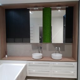 Meblowo Jarosław Warzecha - Nowoczesna łazienka z dwiema okrągłymi umywalkami nablatowymi, minimalistyczną armaturą, drewnianym blatem i białymi szufladami, z dekoracyjnym panelem z mchu na ścianie i czarną żaluzją w tle.