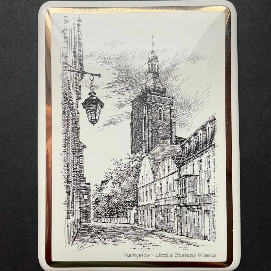 Ręcznie rysowany widok uliczki Starego Miasta w Namysłowie, umieszczony na błyszczącej płytce z pozłacaną obwódką.