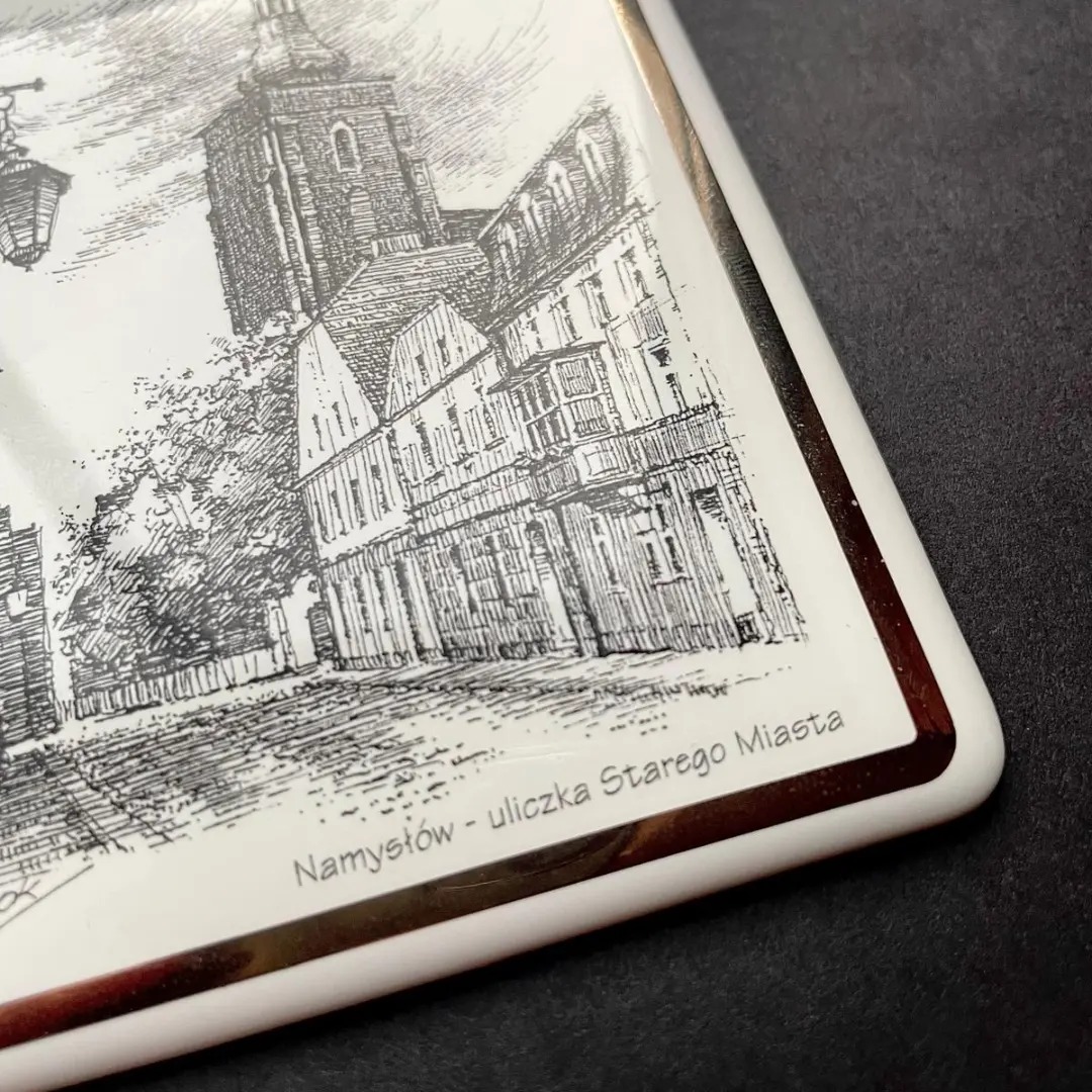 Ręcznie rysowany szkic starego miasta Namysłów na ceramicznej płytce z brązowym obramowaniem.
