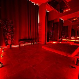 Desert Rose - Wnętrze gabinetu z czerwonym oświetleniem, dekoracyjnymi lampionami, lustrami na suficie i niskim łóżkiem.