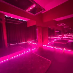 Desert Rose - Pokój do zabiegów z podświetlonymi platformami i lustrami w intensywnym różowym oświetleniu.