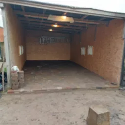 Zadaszona wiata z nowo ułożoną kostką brukową w kolorze cegły, widoczne przygotowania do dalszych prac wykończeniowych.