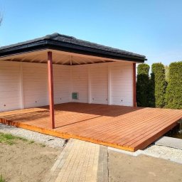 WoodWizard Mariusz Jarosik - Otwarta, drewniana konstrukcja z płaskim dachem i drewnianą podłogą, częściowo otoczona białymi ścianami, przylegająca do oczka wodnego z kaskadą, widoczna z perspektywy ogrodu.