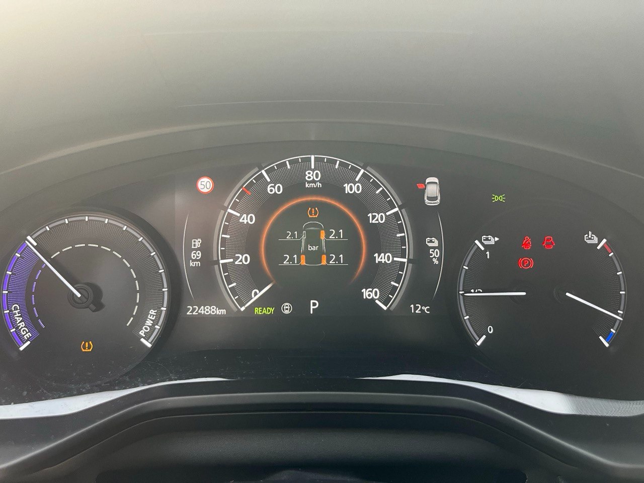 Deska rozdzielcza samochodu z widocznymi wskaźnikami, w tym ciśnienia w oponach, poziomu naładowania baterii i prędkościomierza, przebieg 22488 km.