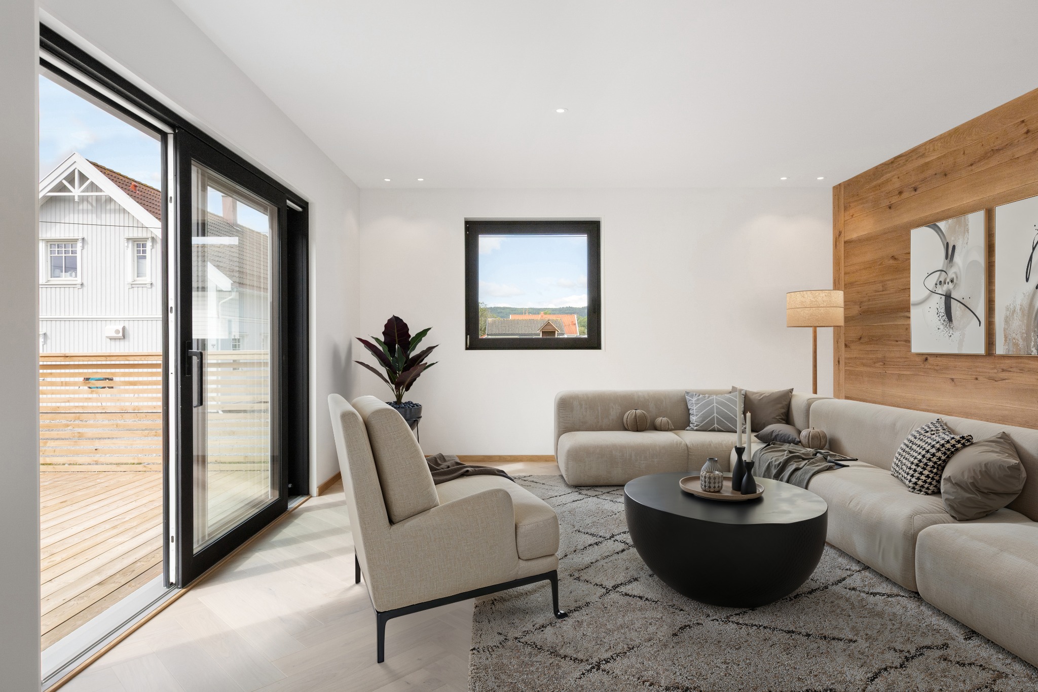 Jasny salon z drewnianą ścianą i wyjściem na taras przez przesuwne drzwi balkonowe. W tle widoczny dom z białymi ścianami i czerwonym dachem.