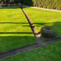 Przygotowany grunt pod trawnik z rolki, widoczne rolki trawy oraz wykopane rowki. Trawa w intensywnym odcieniu zieleni, wysoka jakość wykonania.