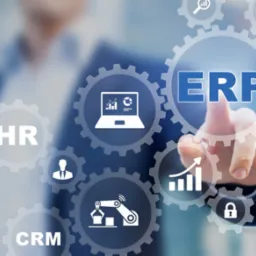 Interfejs użytkownika z ikonami CRM, HR, ERP, laptopa z wykresem, wykresu słupkowego, robota, chmury, lupy i kłódki, dotykany palcem na tle osoby w garniturze.