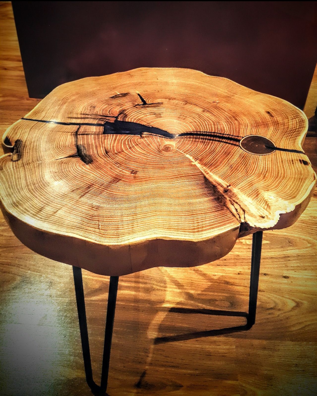 Stolik kawowy z blatem z plastra drewna z żywicą epoksydową wypełniającą pęknięcia, osadzony na metalowych nogach typu hairpin legs.