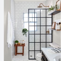 Renowacja Łukaszewicz - Nowoczesna łazienka z kabiną prysznicową typu walk-in z czarnymi ramami, białe płytki metra na ścianach, drewniany stołek z kosmetykami i wzorzysta podłoga w strefie wejścia.