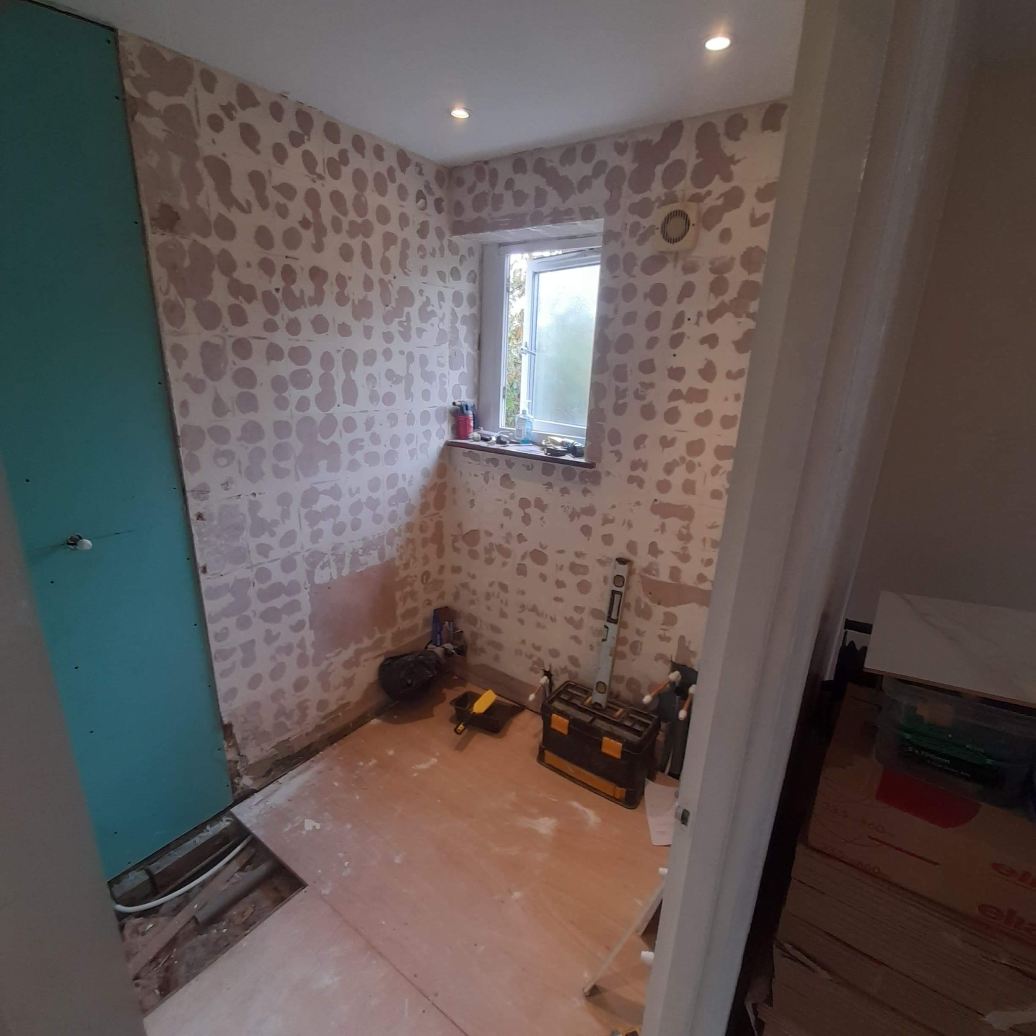 Łazienka w trakcie prac w Jeleniej Górze: ściany przygotowane pod gładzie z widocznymi plamami po szpachlowaniu, częściowo zamontowana płyta karton gips, narzędzia pracy i przygotowane panele...