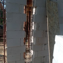 Mirosław Janowski. - Wnęka w ścianie z betonu komórkowego, przygotowana na zbrojenie pionowe, widoczne pręty zbrojeniowe oraz częściowo wypełniona zaprawą, obok leży płyta OSB.