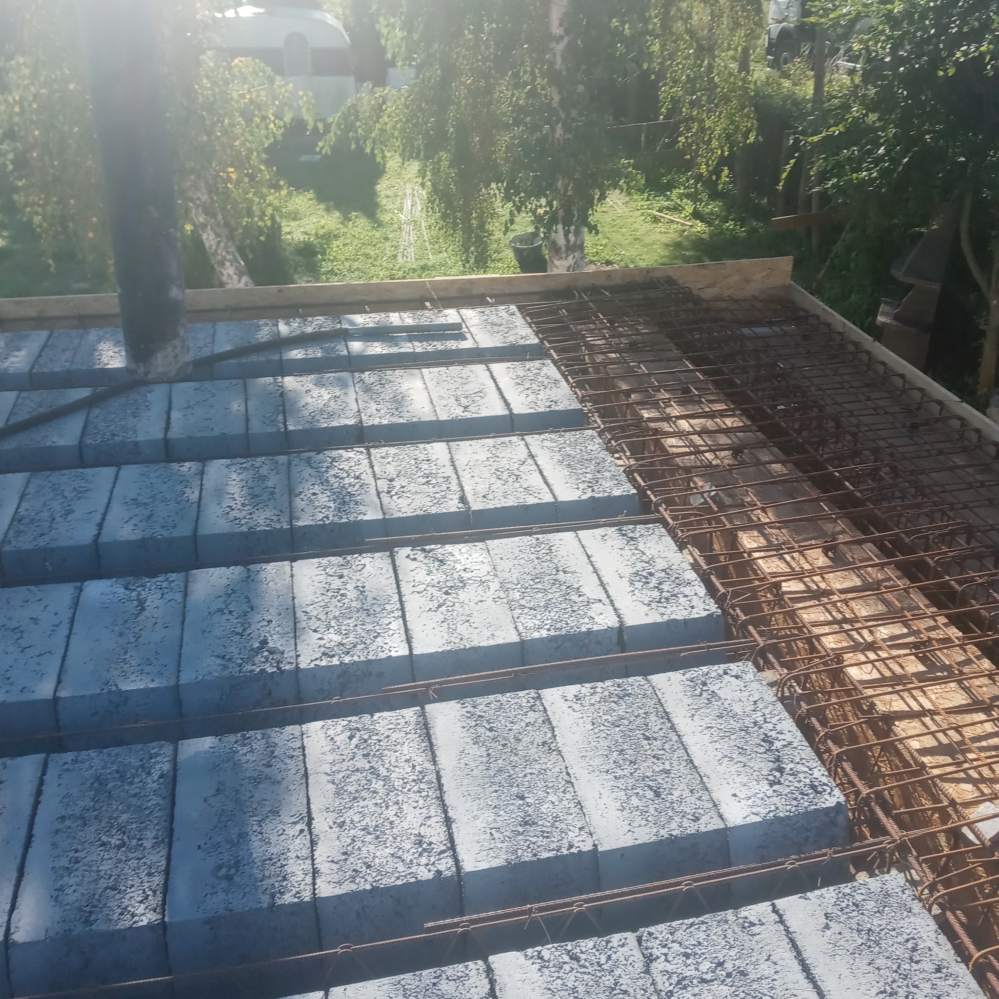 Wieniec stropowy Teriva przed zalaniem betonem, z widoczną siatką zbrojeniową i pustakami stropowymi, w tle zieleń ogrodu.