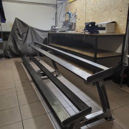 LIONTECH Jakub Kiedrowski - Surowa, metalowa konstrukcja ramy w warsztacie, spawana, z widocznymi narzędziami i stołem roboczym w tle.