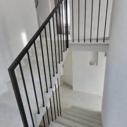 Balustrada z pochwytem 40x40 mm i wypełnieniem 15x15 mm. Tralki mocowane bezpośrednio do ściany, bez dolnego profilu, nadają konstrukcji lekkości. Całość dopełnia dolna harfa z profilu 15x15 mm, mocowana do boku.