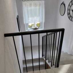 Balustrada z pochwytem 40x40 mm i wypełnieniem 15x15 mm. Tralki mocowane bezpośrednio do ściany, bez dolnego profilu, nadają konstrukcji lekkości. Całość dopełnia dolna harfa z profilu 15x15 mm, mocowana do boku.