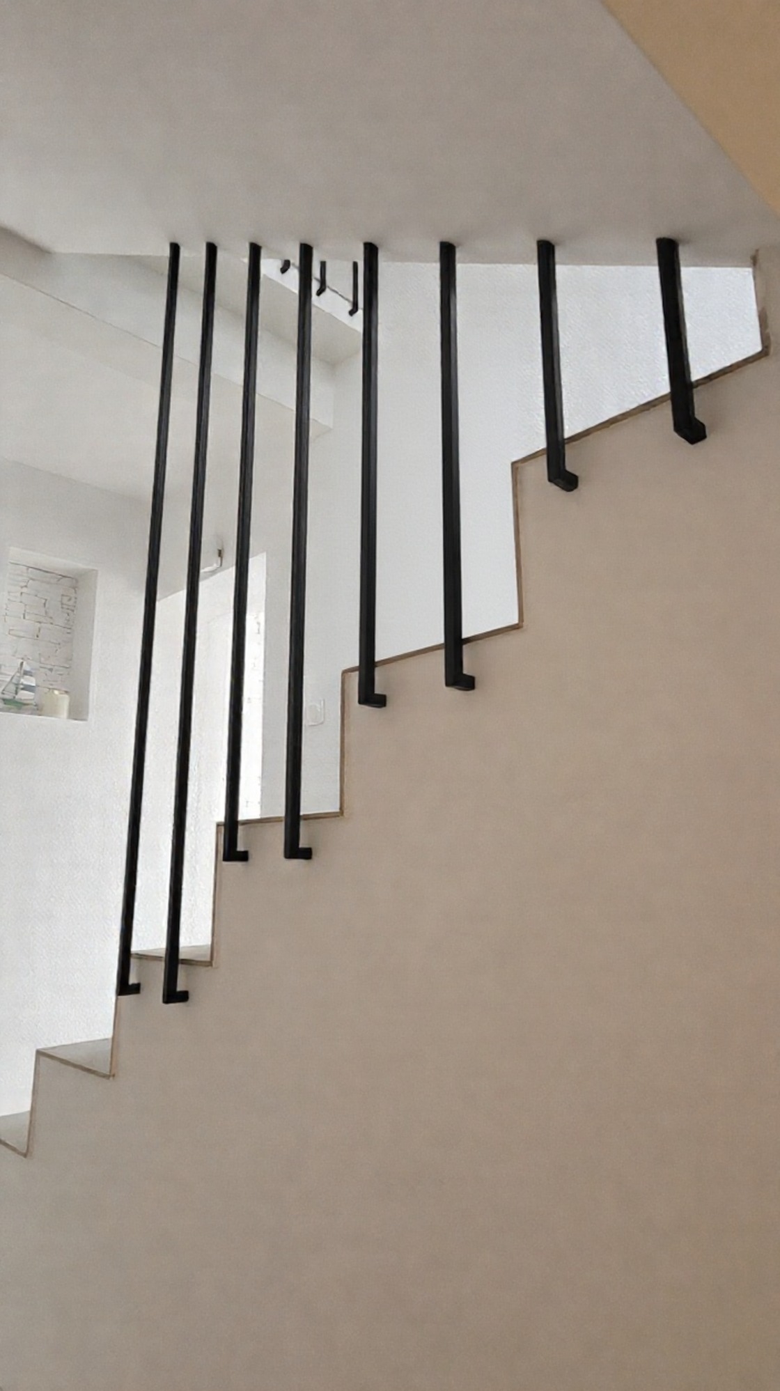 Minimalistyczna balustrada schodowa z czarnymi, pionowymi tralkami, mocowanymi do ściany w Koszalinie. Lekka konstrukcja bez dolnego profilu.